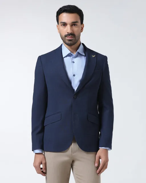 A man in a navy single-breasted blazer over a pale blue shirt