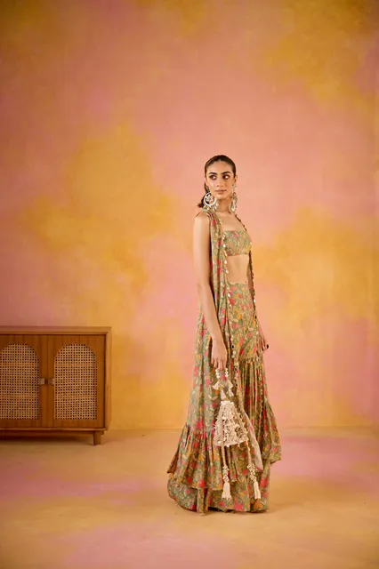 A woman in a green muslin sharara set with a cape