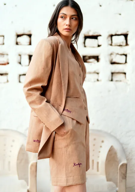 A woman in a sand-coloured linen blazer and shorts set
